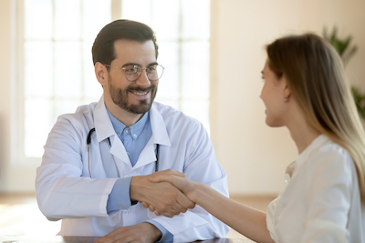 A smiling doctor shaking hands with a patient