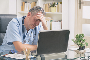 Overworked doctor sitting in his office concerned about ADA compliance