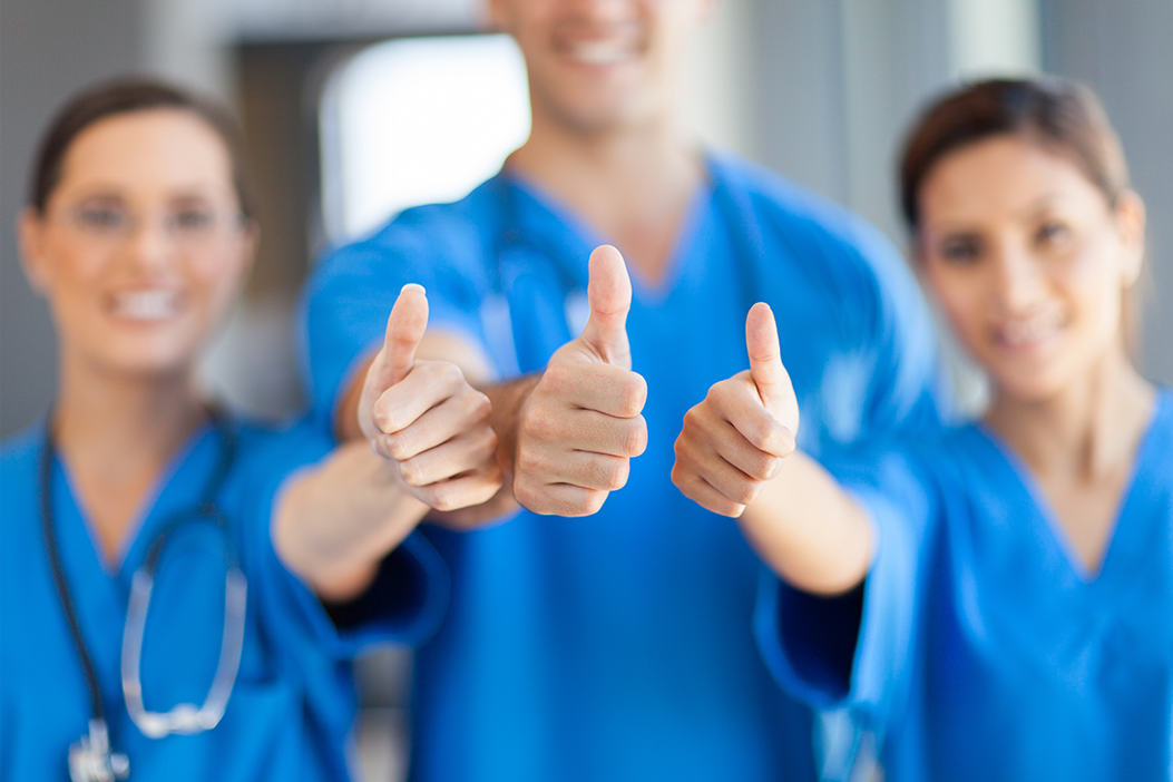 Three medical professionals giving the thumbs up.